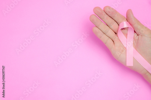 breast cancer awareness ribbon on hand palm and on pink background