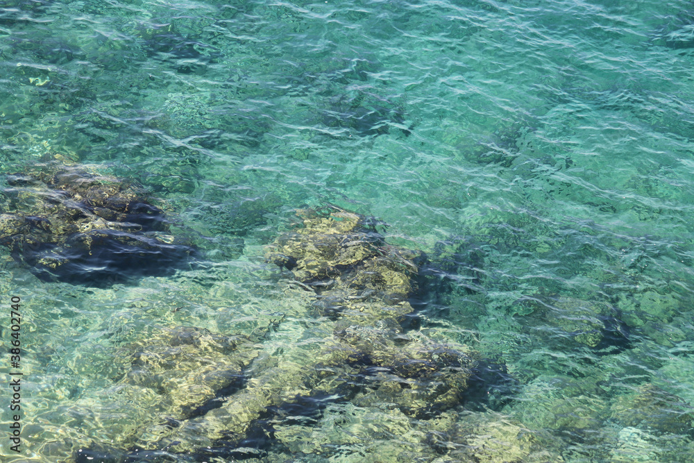 Underwater rocks, transparent sea surface with a rocky bottom.  Aerial view to azure water, natural blue background