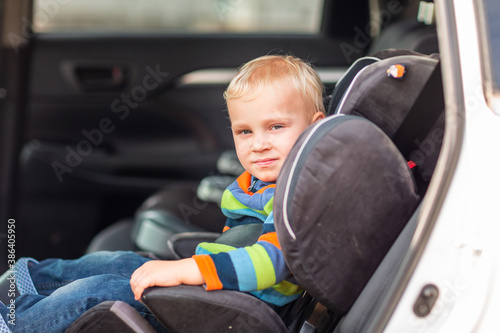 Little baby boy sitting on a car seat buckled up in the car.