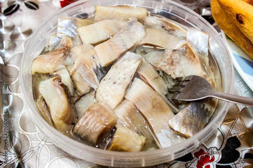 Obraz na płótnie Sliced herring in oil, which is in a plastic jar with a fork.