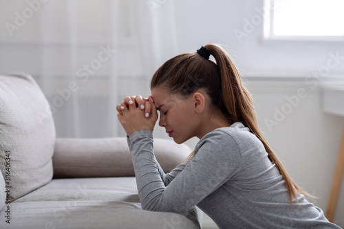 Obraz na plátně Side view of desperate young woman praying to God for help or consolation on sof