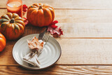 Thanksgiving day serving table with plate, taleware, pumpkins and leaves