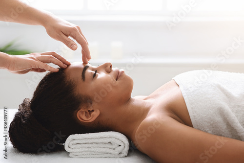 Spa therapist making relaxing head massage for young beautiful lady