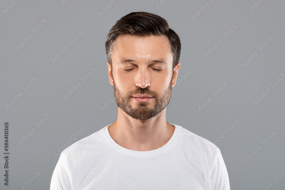 Middle-aged man with closed eyes over grey studio background Middle-aged man with closed eyes over grey studio background