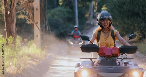 Woman standing hand in the air riding quadbike with friends