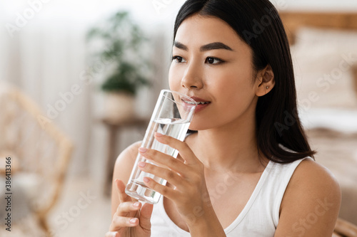 Young attractive asian woman drinking water, copy psace