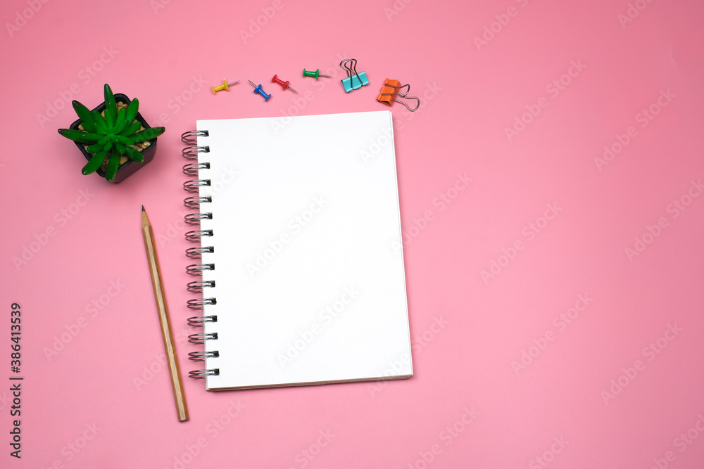 Flat lay, Top view text and leave a message concept on pink table desk background with blank notepad and green plant, pencil and stationeries, copy space