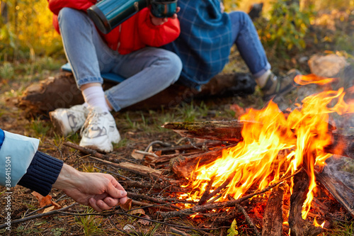close-up photo of male hands trying to light a fire during a trip, adventure or hiking in mountains, sit next to bonfire