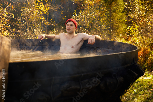 young man enjoy spending time in bath outdoors in the forest, relax hot water inside of bath
