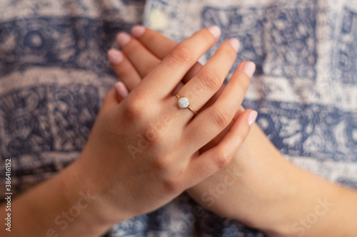 Woman hands with gold ring folded for a prayer against shirt. Close-up..