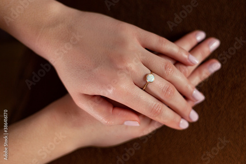 Woman s hands with gold ring on her middle finger against dark background.
