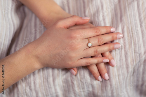 Woman hands with golden ring on the middle finger against light background.