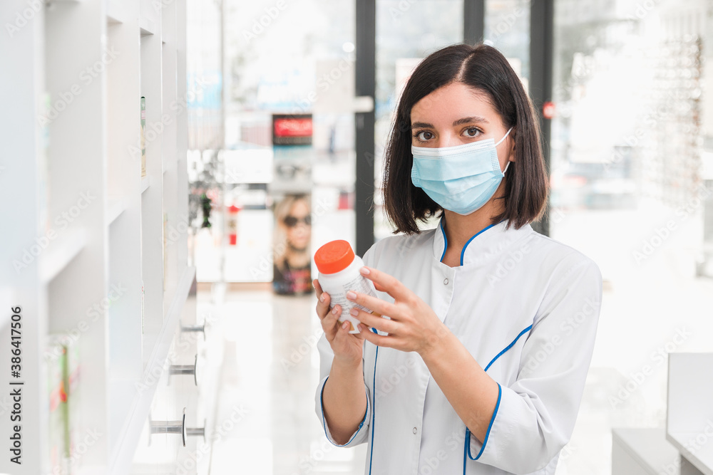 attractive ethnicity female pharmacist wearing medicine mask holding a pill container with antiviral medicine attractive ethnicity female pharmacist wearing medicine mask holding a pill container with antiviral medicine