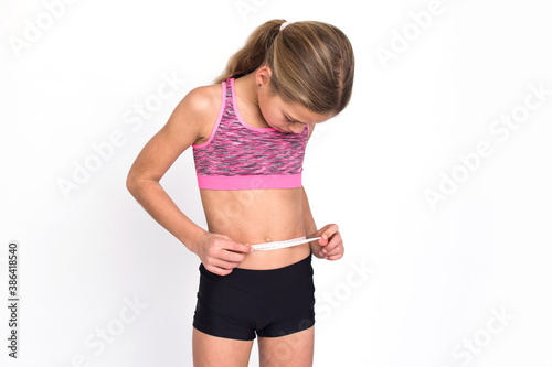 Wallpaper Mural Slim young girl is measuring her waist isolated on white background. Female person in sportswear have calories loss and tape measure. Health and diet concept with copy space. Torontodigital.ca