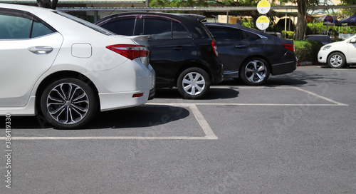 Closeup of rear side of white car with  other cars parking in outdoor parking area in bright sunny day.  © Amphon