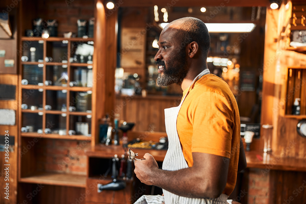 Handsome Afro American man with hair trimmer standing in barbershop Handsome Afro American man with hair trimmer standing in barbershop