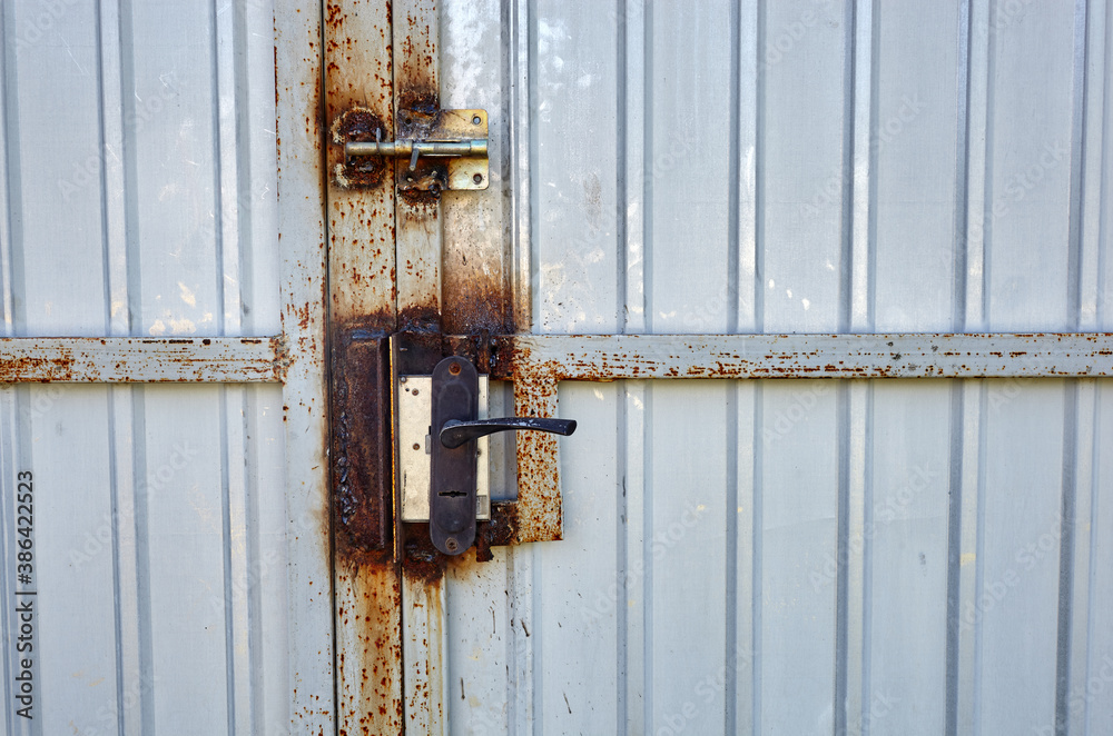 Iron rusty fence with a lock. White corrugated metal or zinc texture surface or galvanize steel in the vertical line background Iron rusty fence with a lock. White corrugated metal or zinc texture surface or galvanize steel in the vertical line background