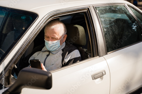 elderly caucasian man sitting in car and using phone. active modern pension people
