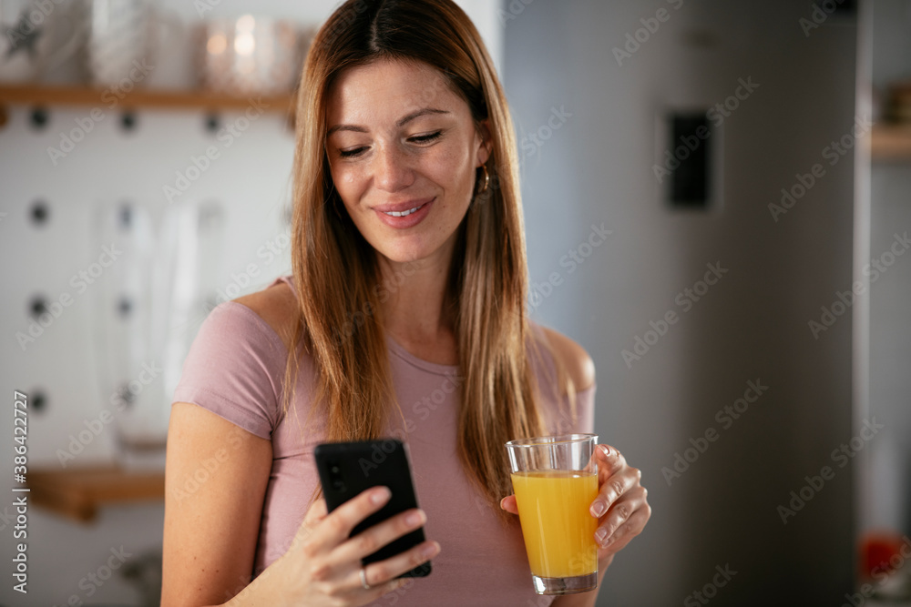 Young woman in kitchen. Beautiful woman preparing breakfast and using the phone. Young woman in kitchen. Beautiful woman preparing breakfast and using the phone.