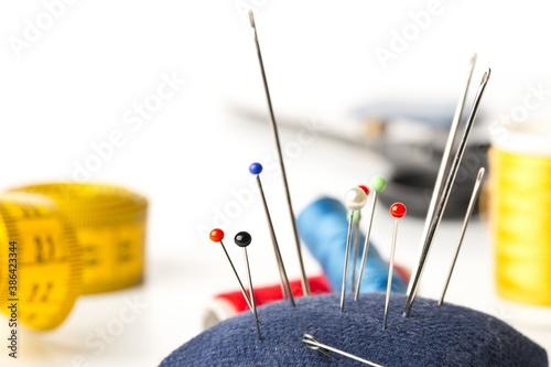 Schilderij op canvas Close up of collection of sewign needles with sewing tools in the background ove