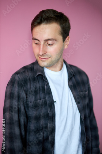 portrait of young caucasian trendy guy in checkered casual shirt, isolated on pink background