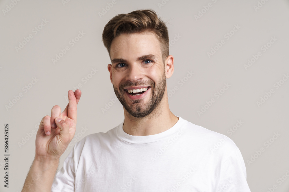 Fototapeta premium Joyful handsome guy posing with fingers crossed for good luck