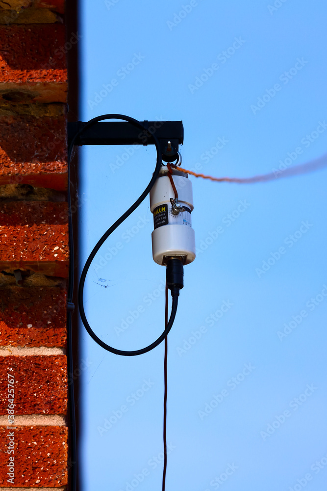 Amateur radio long wire HF dipole antenna and balun fixed to the side of a house wall Stock Photo Adobe Stock image