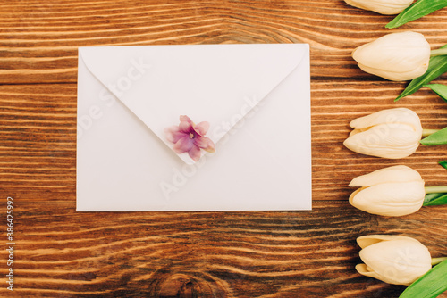 Fototapeta Naklejka Na Ścianę i Meble -  top view of envelope near tulips on wooden background