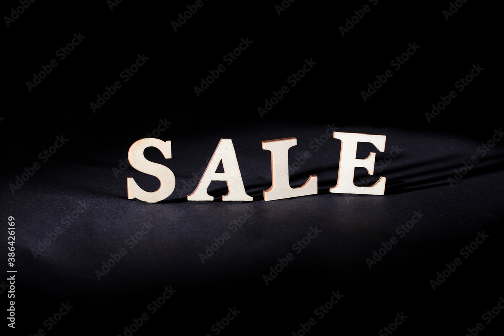 Obraz premium Word sale from wooden letters on a black background. Discounts and sales concept