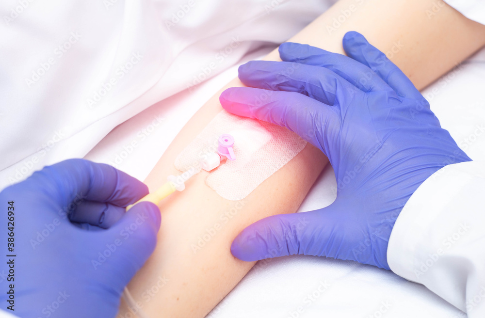 Doctor inserting an intravenous catheter for blood transfusion into a patient, close-up. Blood donation Doctor inserting an intravenous catheter for blood transfusion into a patient, close-up. Blood donation