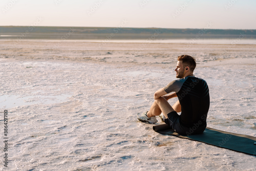 Attractive young sportsman sitting at the salt lake
