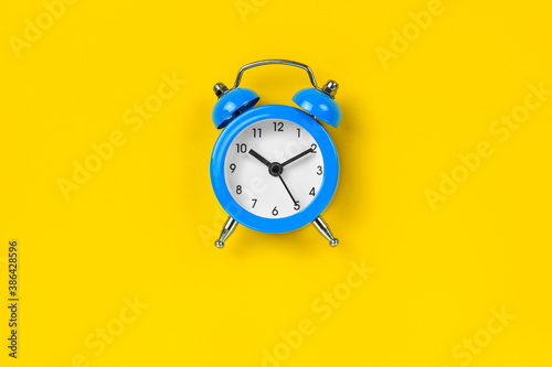 Blue alarm clock on yellow background