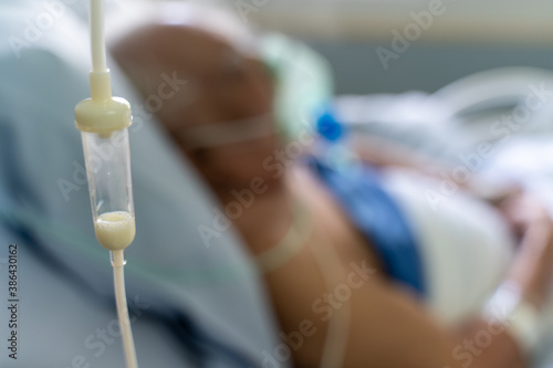 Enteral feeding dropper and a old man patient in the hospital with oxygen mask in the background