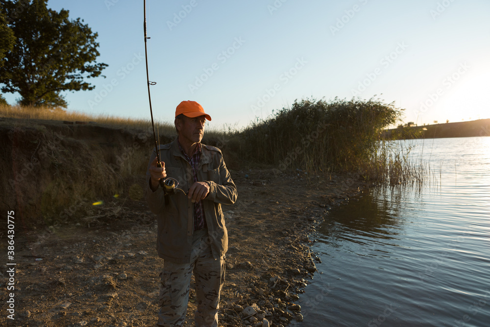 Fisherman standing on the riverside and trying to catch a fish. Sport, recreation, lifestyle. Fisherman standing on the riverside and trying to catch a fish. Sport, recreation, lifestyle.