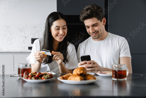 Cheerful young couple having tasty breakfast