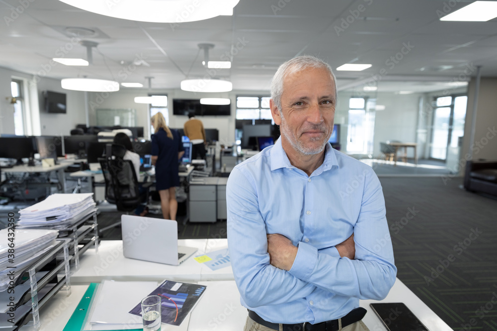 Portrait of senior businessman with arms crossed  at modern office