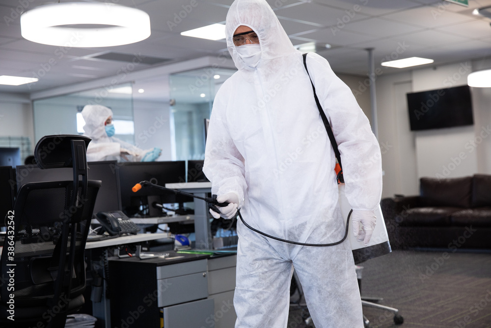 Health worker wearing protective clothes cleaning the office using disinfectant Health worker wearing protective clothes cleaning the office using disinfectant