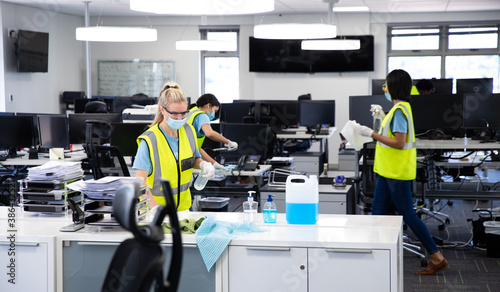 Photography Team wearing hi vis vest and face mask cleaning the office using disinfectant