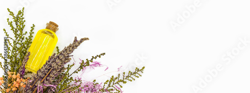 Fotografie Top view of bottle with natural yellow oil next to dry lavender with flowers on white background