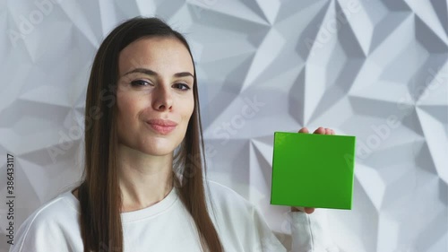 Beautiful brunette girl in white as a doctor holds and demonstrates a box for advertising a product, a green screen for demonstrating a product