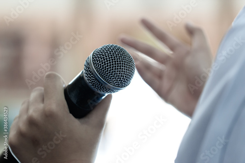 Smart businessman speaker speech with microphone at seminar conference and speaking with mic in auditorium room while explaining or gesturing in event light convention hall Background