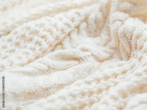 Hand made cable-knit sweater sweater. Texture of warm knitted fabric with pattern. White crumpled cardigan. Cozy autumn outfit for snuggle weather.