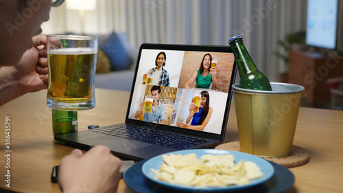 Photography Attractive young happy asian man enjoy relax night party event online celebration festive with friends at home clinking beer with glass and bottle toasting drinking via video call