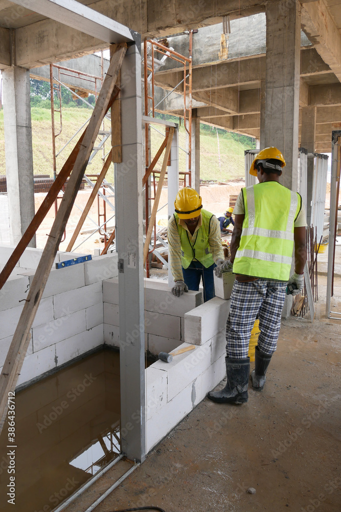 SEREMBAN, MALAYSIA -MARCH 16, 2020: Construction workers laying autoclaved aerated concrete block at the construction site. The use of this material can save time and facilitate construction work. SEREMBAN, MALAYSIA -MARCH 16, 2020: Construction workers laying autoclaved aerated concrete block at the construction site. The use of this material can save time and facilitate construction work.