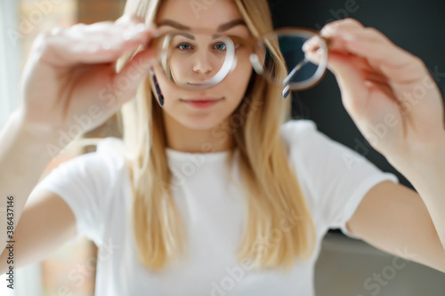 A woman has vision problems, squints when trying to see something, takes off her glasses, is isolated. Myopia, hyperopia, vision concept. High quality photo.