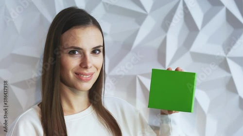 Beautiful brunette girl in white as a doctor holds and demonstrates a box for advertising a product, a green screen for demonstrating a product
