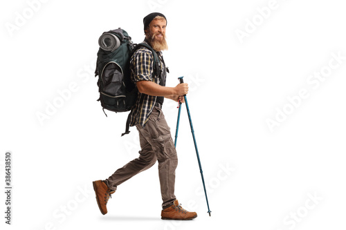 Full length profile shot of a bearded guy hiker with a backpack and hiking poles walking photo