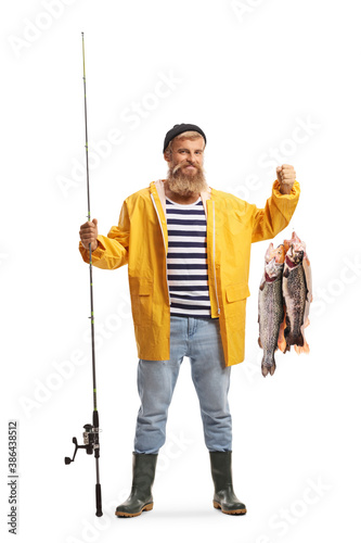 Full length portrait of a fisherman in a yellow rain coat holding a fishing pole and fish