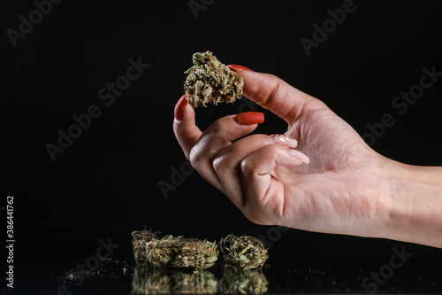 Woman hand holding cannabis on a black background. Marijuana legalization. Medical cannabis. Drug addiction. 