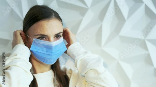 A beautiful brunette girl in white as a doctor puts on a mask, showing safety from a viral pandemic, this is safety from covid, and will stop lockdown, against a white volumetric background